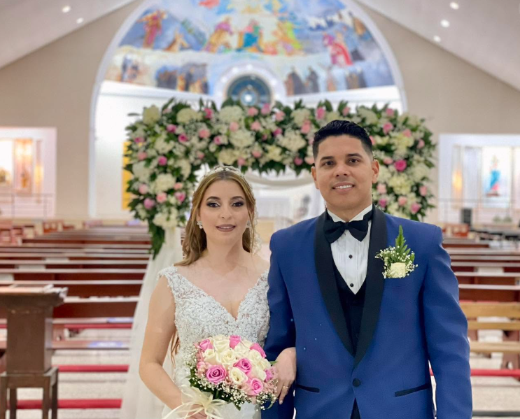 Novios posando frente al arco floral de la iglesia después de la ceremonia