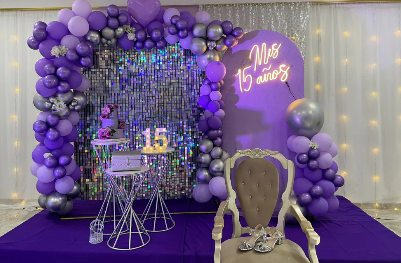 Montaje de quince años con arco de globos lila y plata y letrero de neón