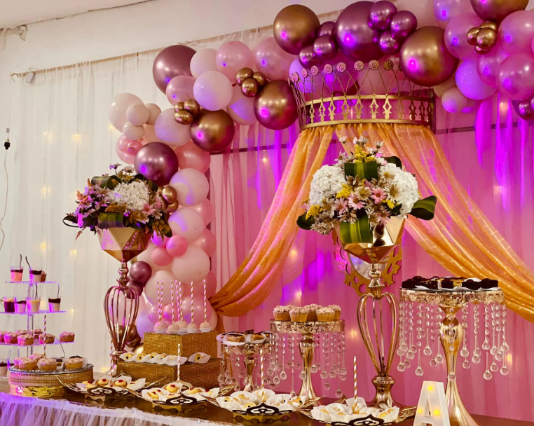 Mesa de dulces de quince años con arreglos florales y bases doradas